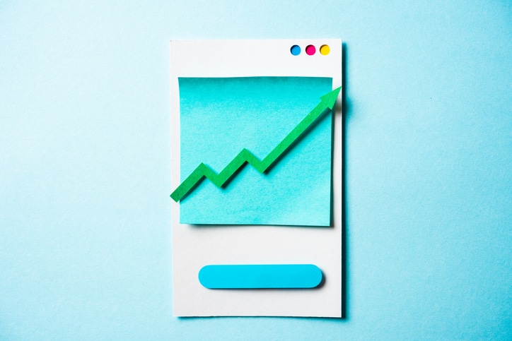 Paper green arrow growing up on smartphone and blue background. Growth business graph chart, stock market investment trading and trends concept as metaphor for the BankingHub media